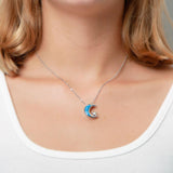 The picture shows a model wearing a 925 sterling silver opalite moon and star pendant with topaz.