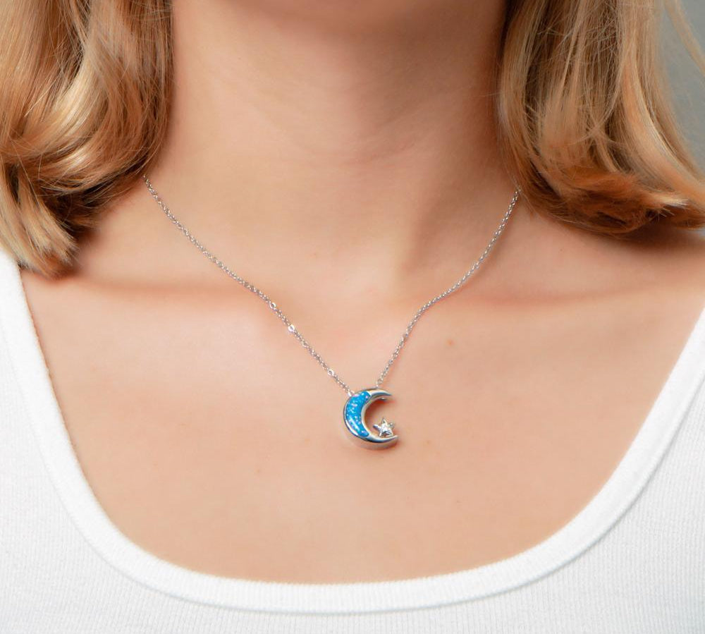 The picture shows a model wearing a 925 sterling silver opalite moon and star pendant with topaz.