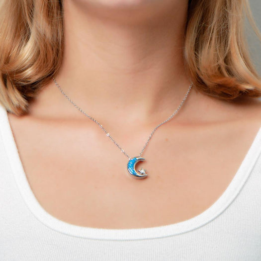 The picture shows a model wearing a 925 sterling silver opalite moon and star pendant with topaz.