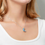 The picture shows a model wearing a 925 sterling silver opalite moon and star pendant with topaz.