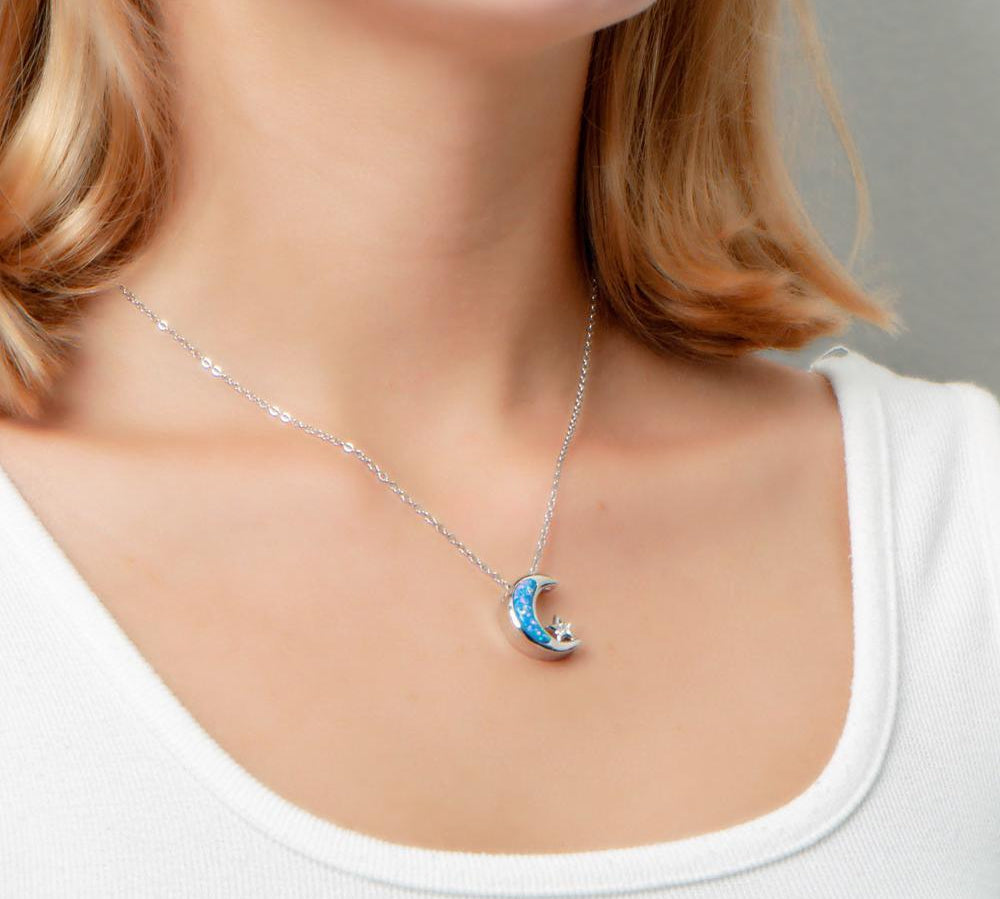 The picture shows a model wearing a 925 sterling silver opalite moon and star pendant with topaz.