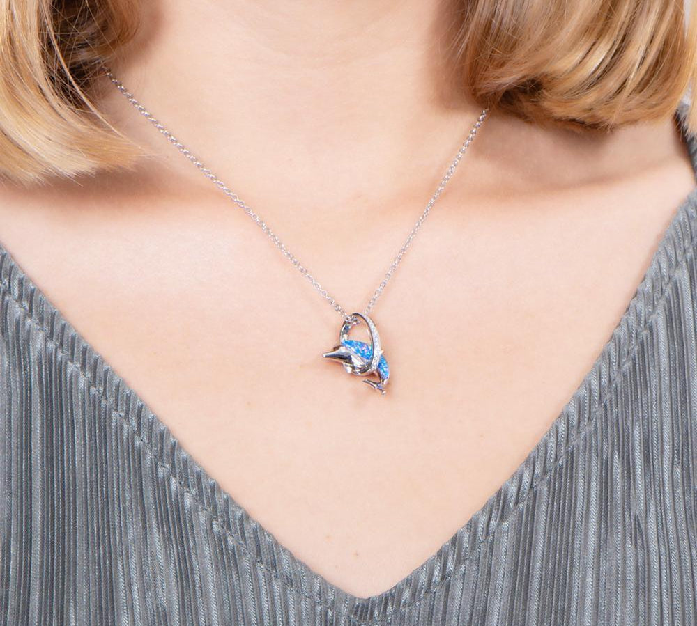 The picture shows a model wearing a 925 sterling silver opalite dolphin through a circle pendant with topaz.