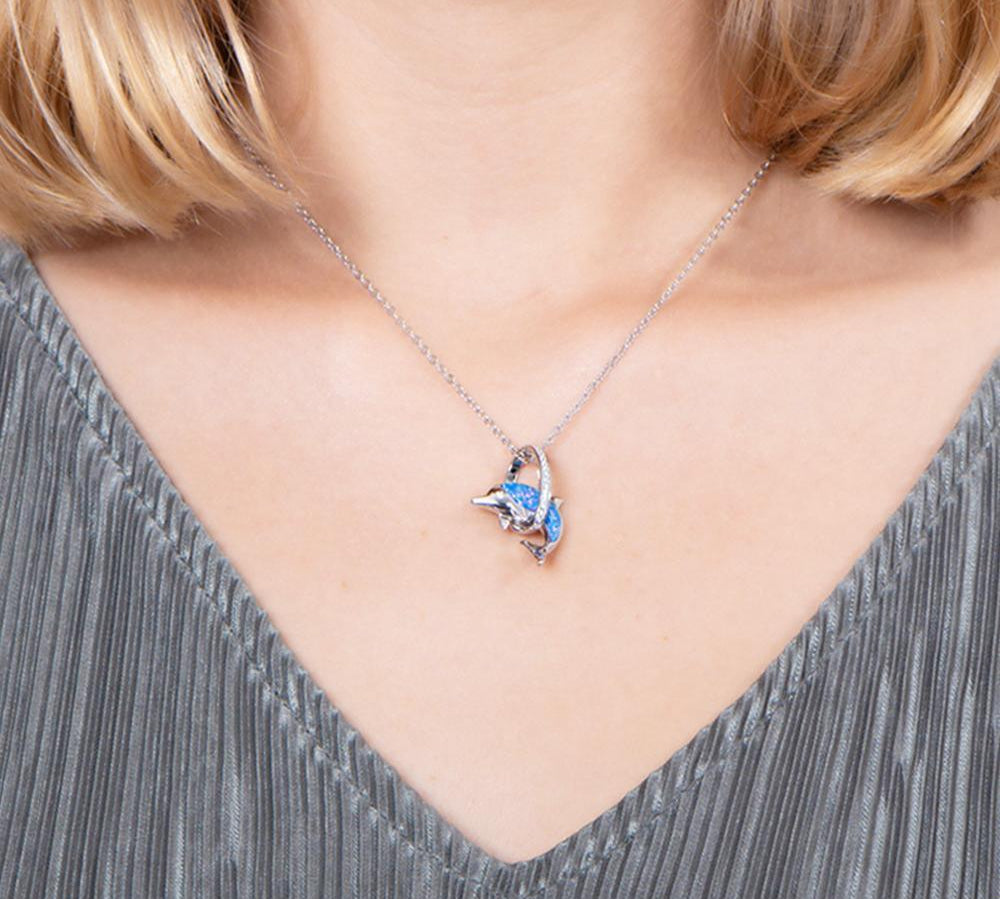 The picture shows a model wearing a 925 sterling silver opalite dolphin through a circle pendant with topaz.