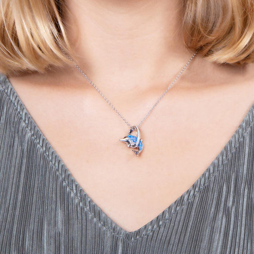 The picture shows a model wearing a 925 sterling silver opalite dolphin through a circle pendant with topaz.