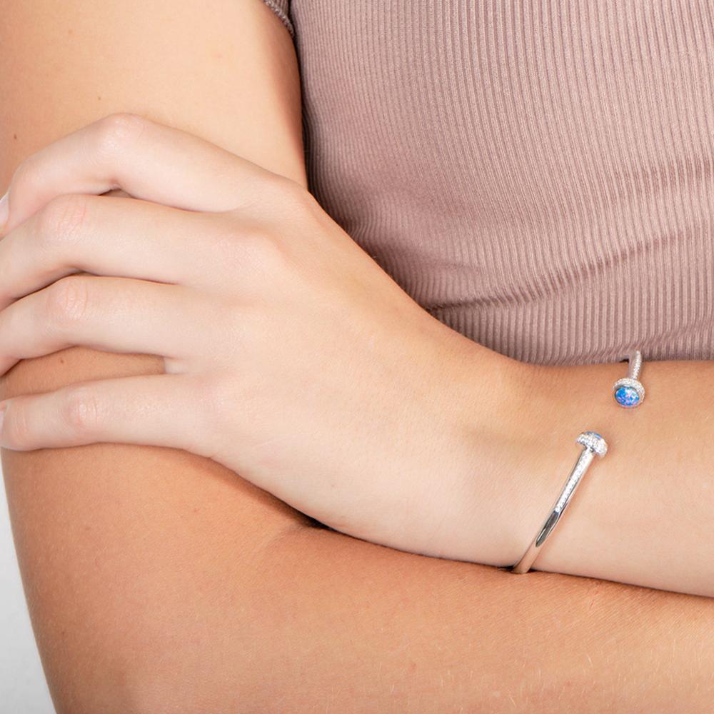 The picture shows a model wearing a 925 sterling silver bangle with two opalite gemstones and topaz.