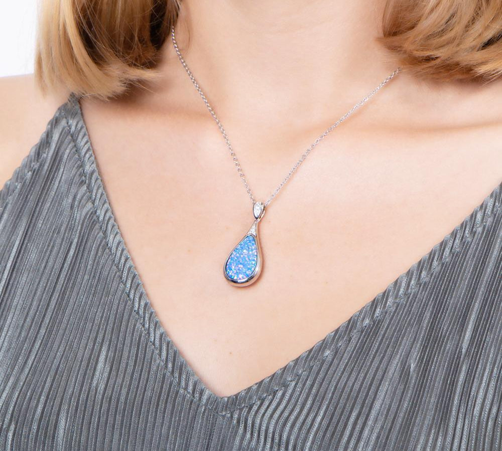 The picture shows a model wearing a 925 sterling silver opalite teardrop pendant with topaz.