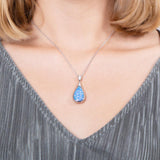 The picture shows a model wearing a 925 sterling silver opalite teardrop pendant with topaz.