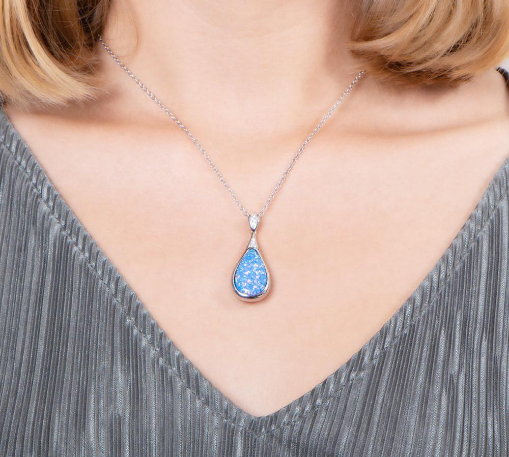 The picture shows a model wearing a 925 sterling silver opalite teardrop pendant with topaz.