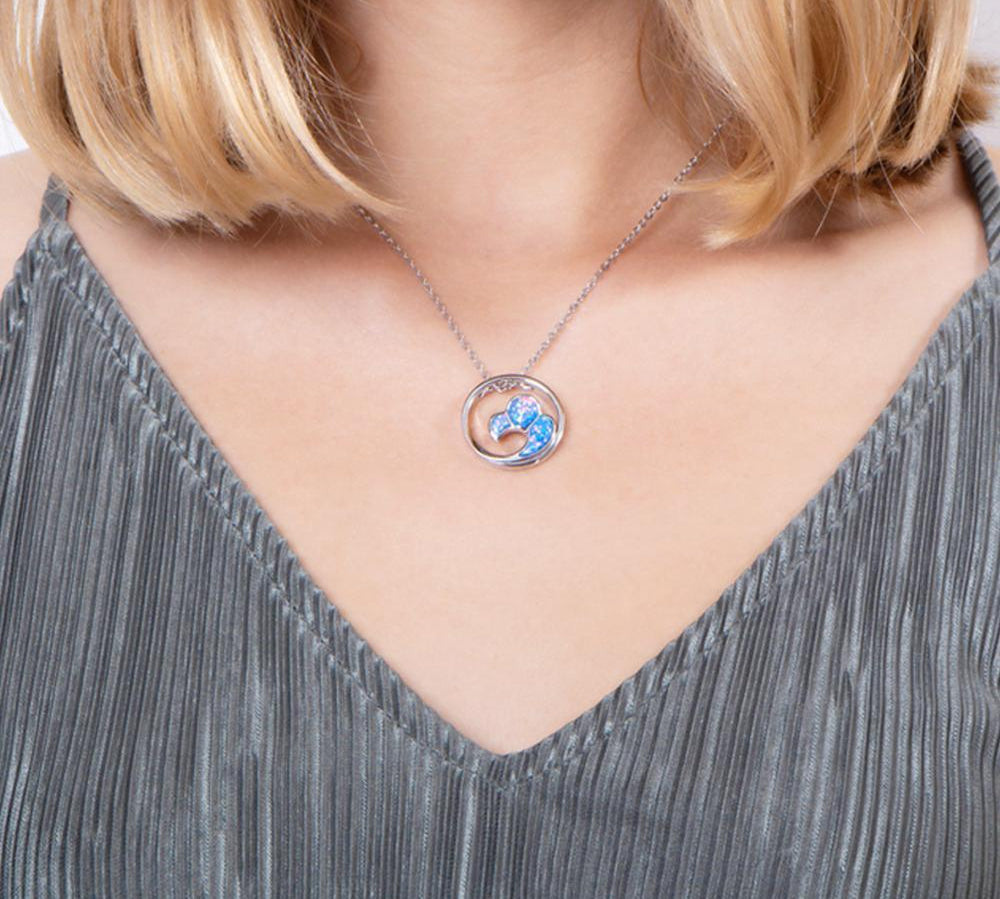 In this photo there is a model with blonde hair and a gray shirt, wearing a sterling silver big wave circle pendant with blue opalite gemstones.