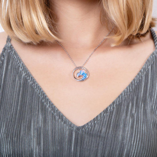 In this photo there is a model with blonde hair and a gray shirt, wearing a sterling silver big wave circle pendant with blue opalite gemstones.