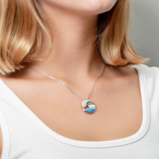 The picture shows a model wearing a 925 sterling silver opalite ocean wave pendant with cubic zirconia.