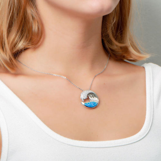 The picture shows a model wearing a 925 sterling silver opalite ocean wave pendant with cubic zirconia.