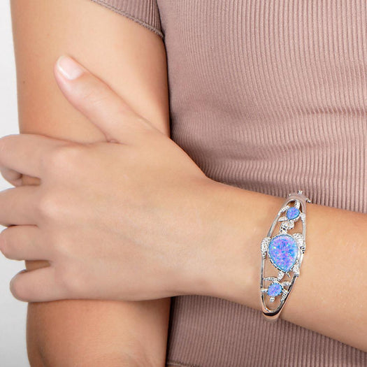 The picture shows a model wearing a 925 sterling silver family of three sea turtles bangle with opalite.