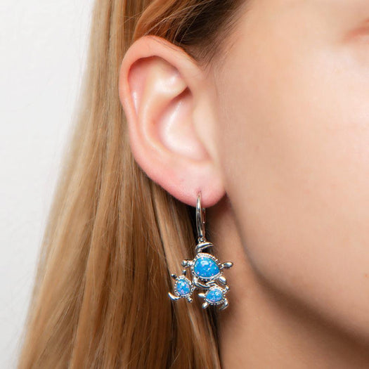 The picture shows a model wearing a 925 sterling silver opalite family of sea turtles earring.