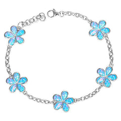 In this photo there is a sterling silver charm bracelet with five plumeria flowers and blue opalite gemstones.