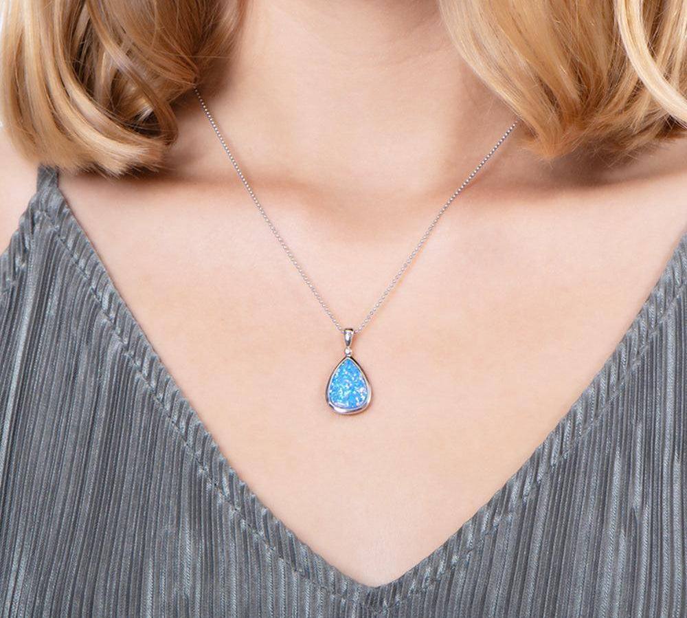 The picture shows a model wearing a 925 sterling silver opalite reuleaux teardrop pendant with cubic zirconia.