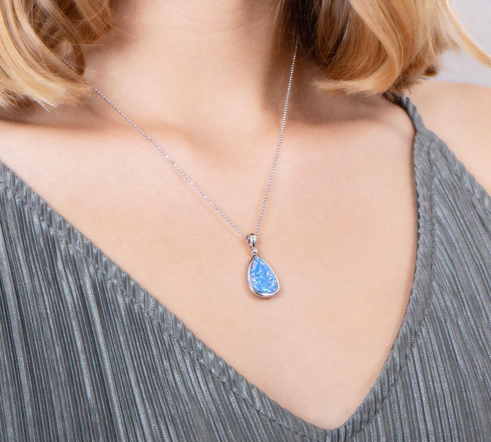 The picture shows a model wearing a 925 sterling silver opalite reuleaux teardrop pendant with cubic zirconia.