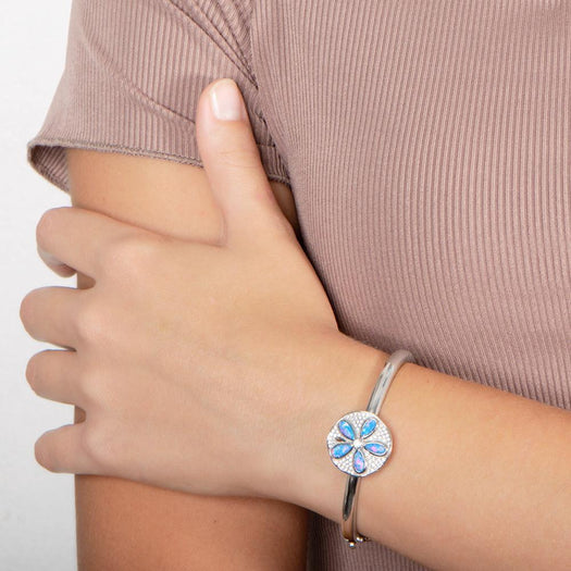 The picture shows a model wearing a 925 sterling silver sand dollar bangle with blue opalite and topaz.