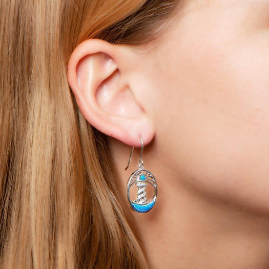 In this photo there is a close-up of a model with blonde hair wearing sterling silver shining lighthouse hook earrings with blue opalite and topaz gemstones.