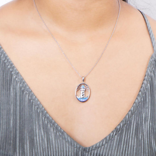In this photo there is a model with a gray shirt wearing a sterling silver shining lighthouse pendant with blue opalite and topaz gemstones.
