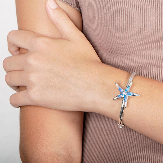 The picture shows a model wearing a 925 sterling silver opalite sea star bangle bangle with topaz.