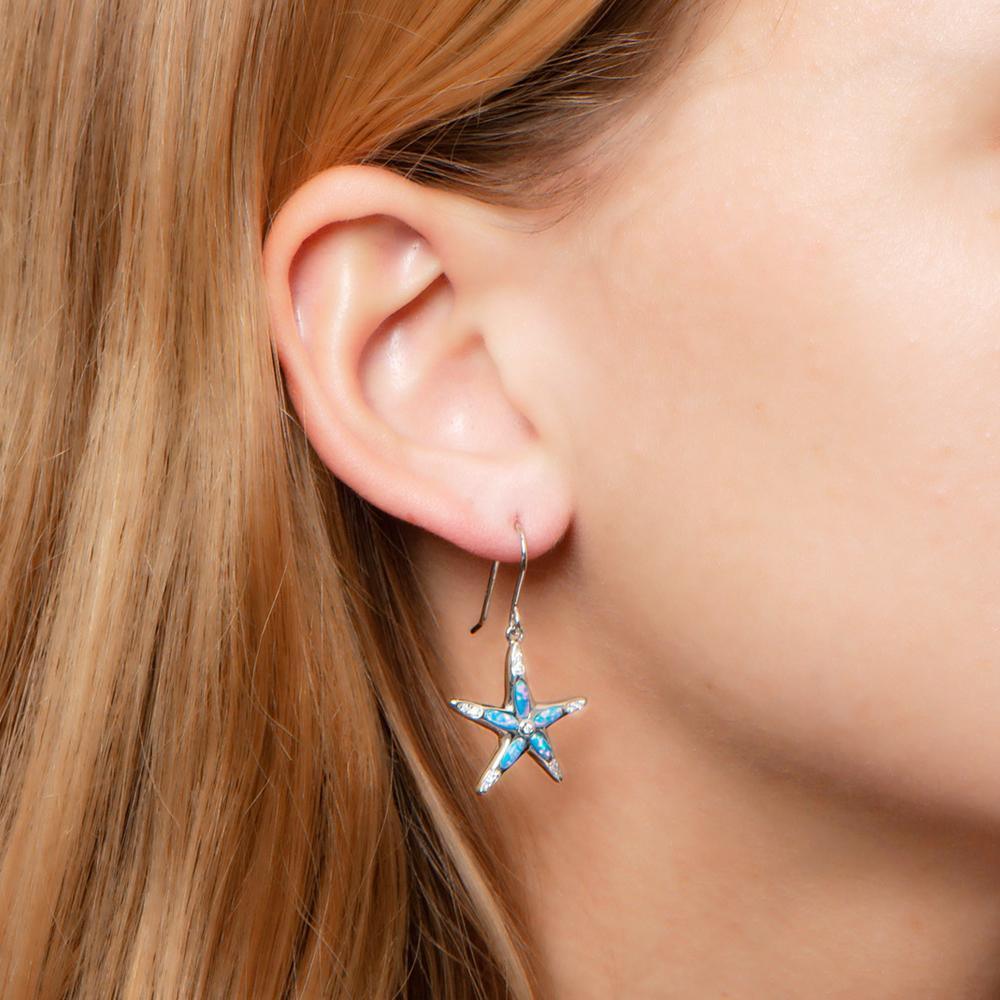 The picture shows a model wearing a 925 sterling silver opalite sea star earring with topaz.