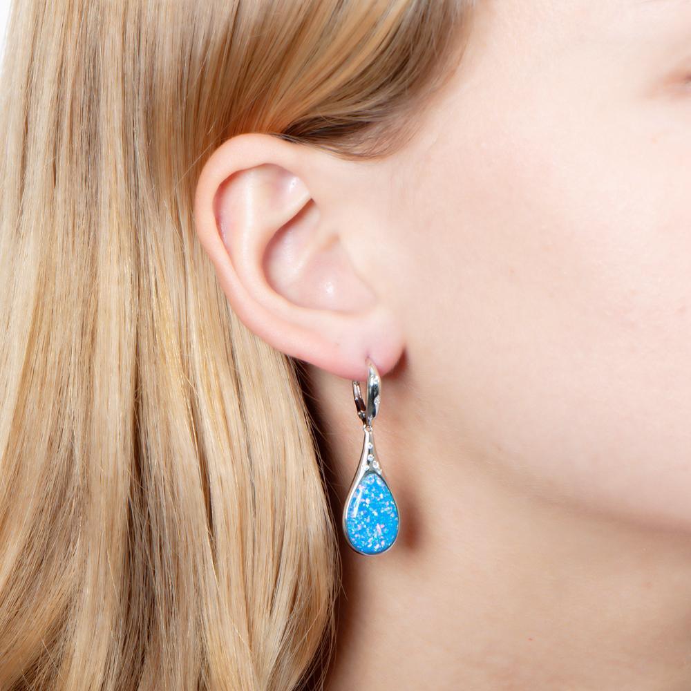 The picture shows a model wearing a 925 sterling silver opalite teardrop earring with topaz.