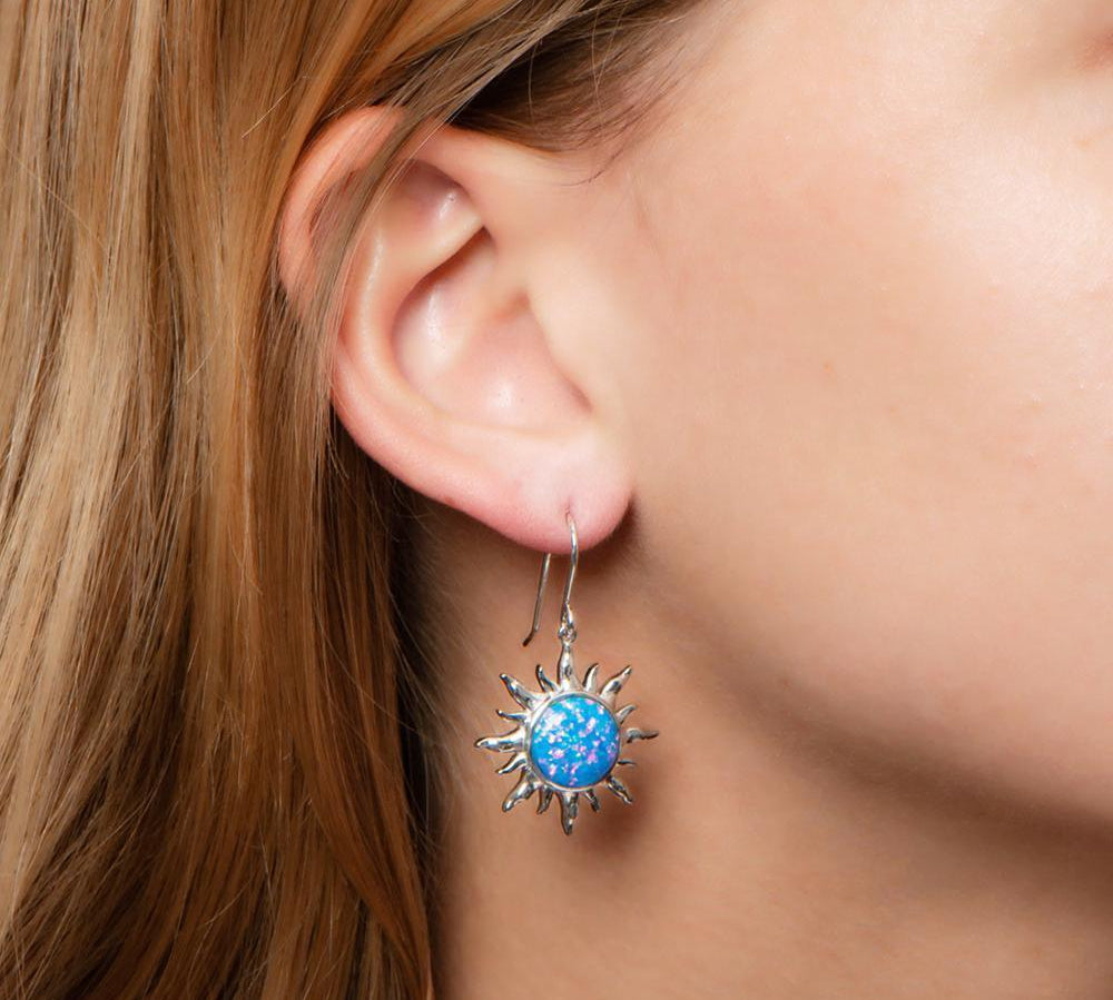 In this photo there is a close-up of a model with blonde hair wearing sterling silver sun hook earrings with blue opalite gemstones.