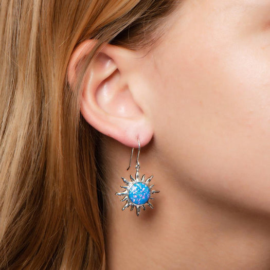 In this photo there is a close-up of a model with blonde hair wearing sterling silver sun hook earrings with blue opalite gemstones.