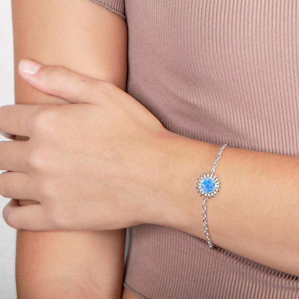 In this photo there is a model wearing a 925 sterling silver sunflower bracelet with one blue opalite gemstone