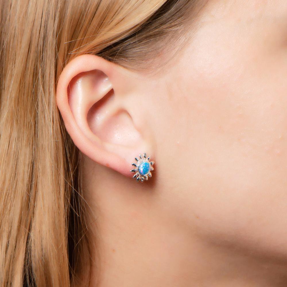 In this picture there is a close up of a model turned to the side with blonde hair wearing sunflower stud earrings with blue opalite set in sterling silver.