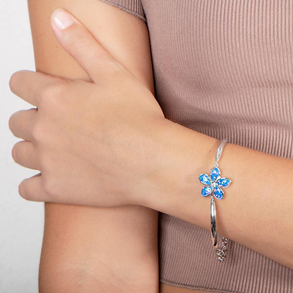 In this photo there is a model wearing a 925 sterling silver plumeria bracelet with blue opalite gemstones