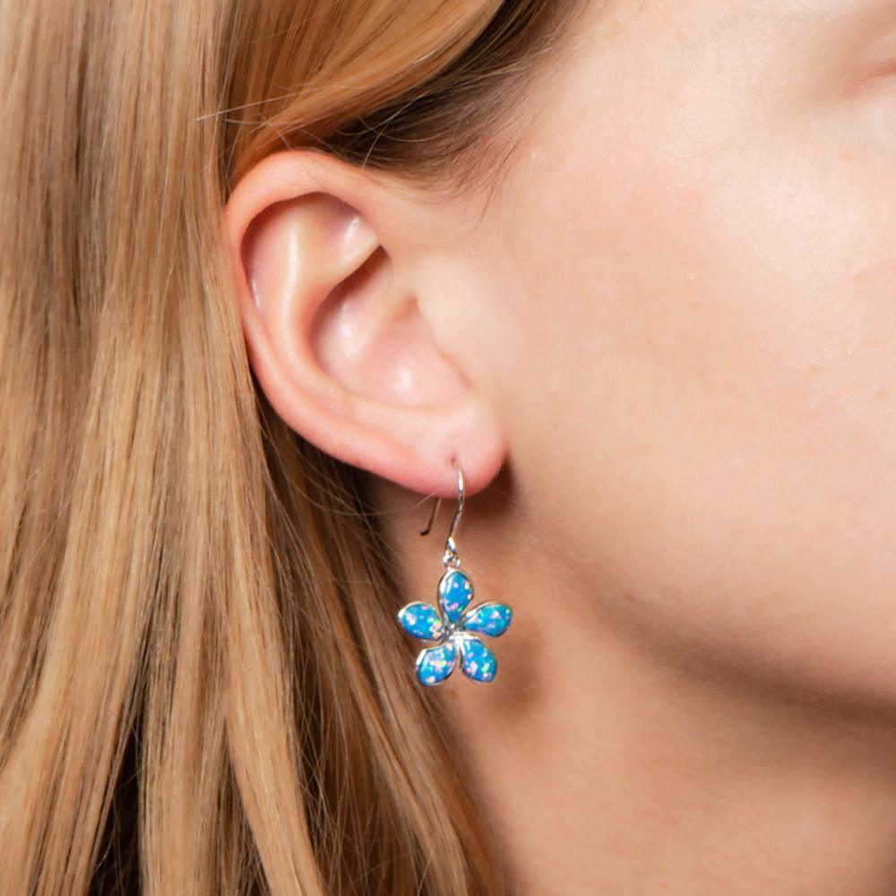 In this photo there is a close-up of a model with strawberry blonde hair wearing sterling silver plumeria hook earrings with blue opalite gemstones.