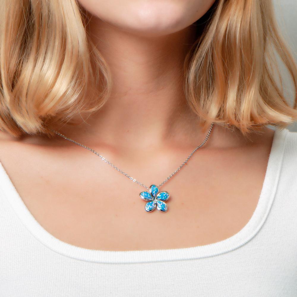In this picture there is a model with blonde hair and a white shirt, wearing a plumeria pendant with blue opalite set in sterling silver.