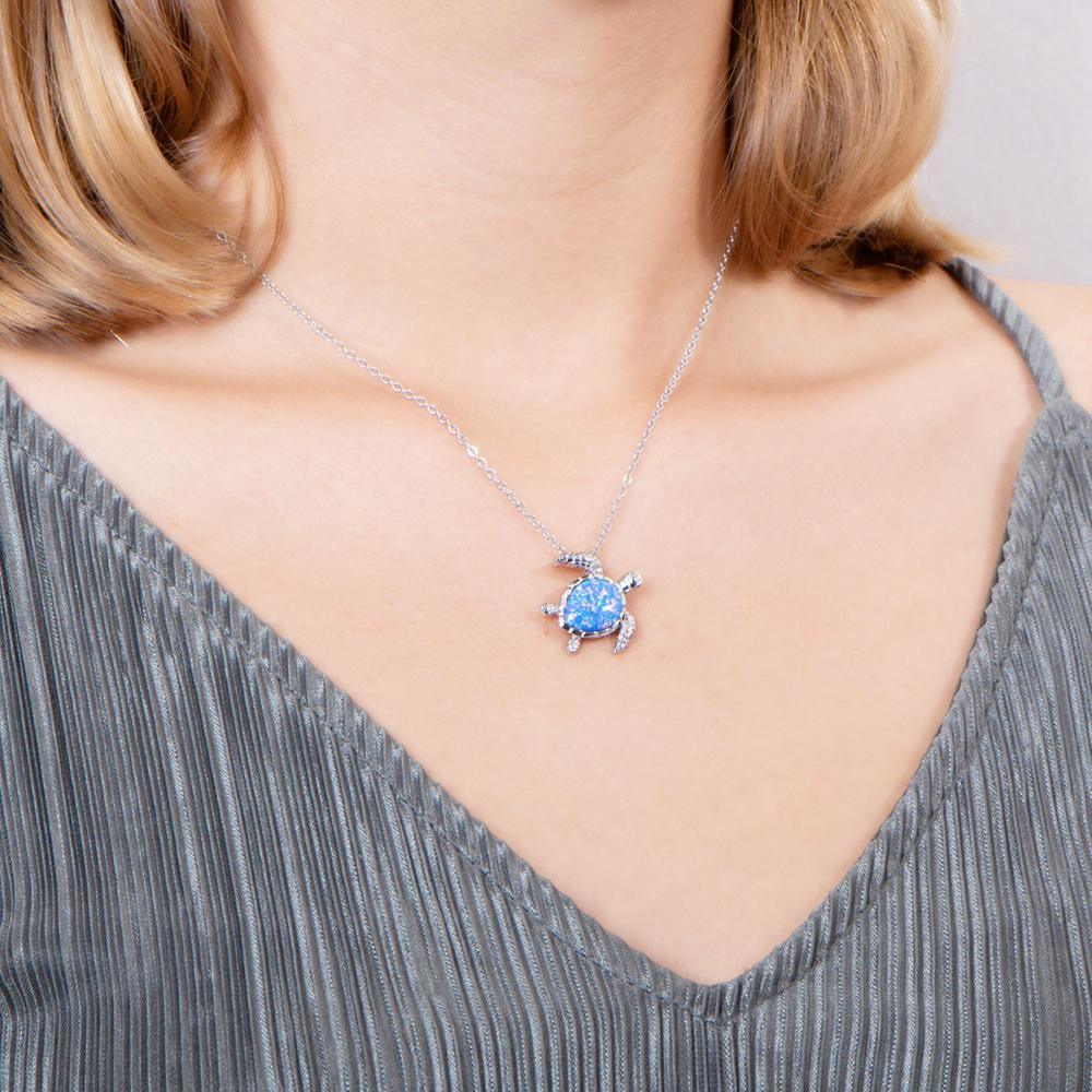 The picture shows a model wearing a 925 sterling silver opalite swimming sea turtle pendant and topaz.