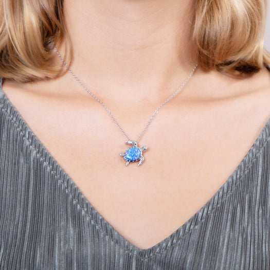 The picture shows a model wearing a 925 sterling silver opalite swimming sea turtle pendant and topaz.