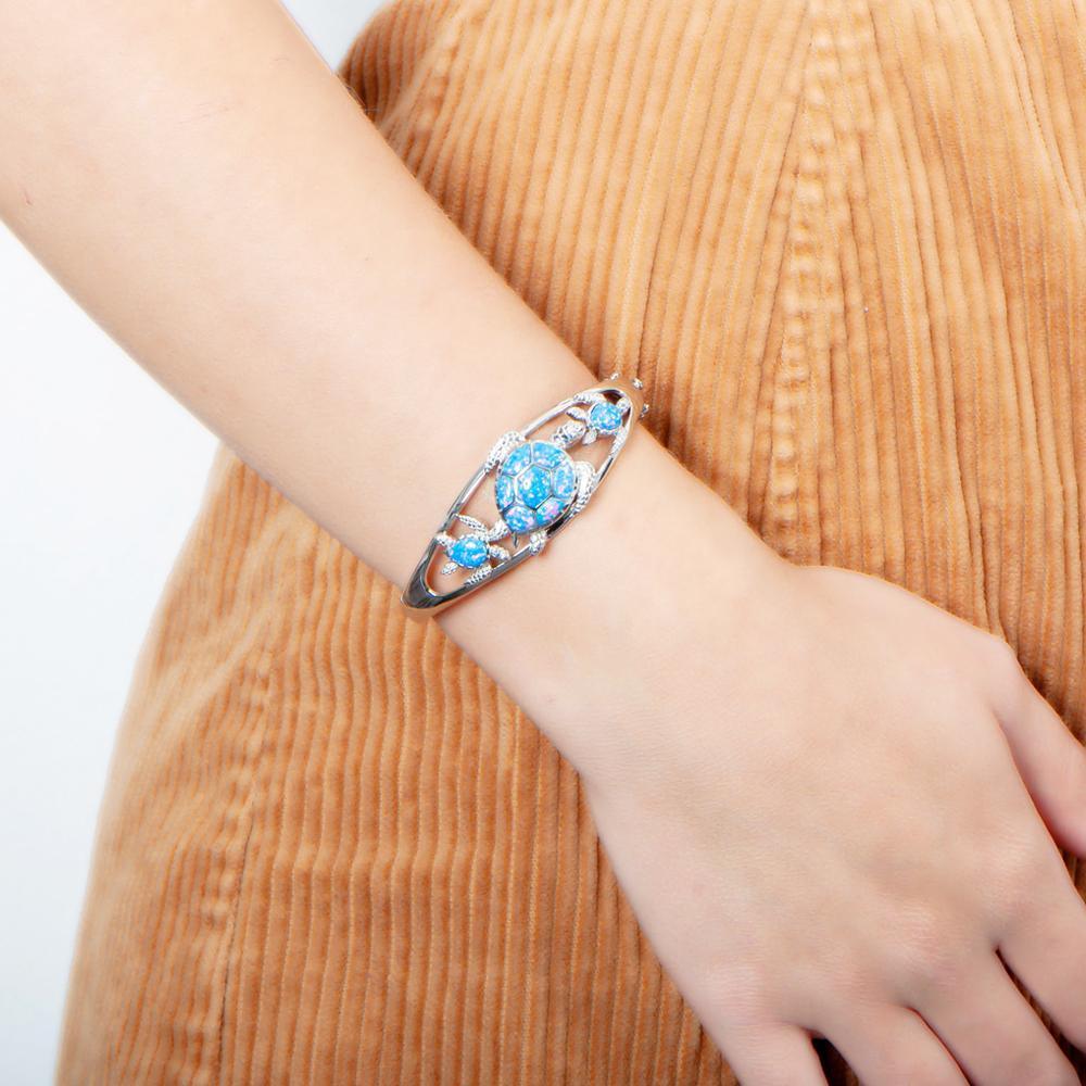 The picture shows a model wearing a 925 sterling silver opalite three sea turtle bangle.