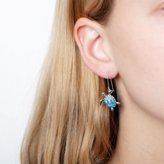 The picture shows a model wearing a 925 sterling silver opalite sea turtle earring.