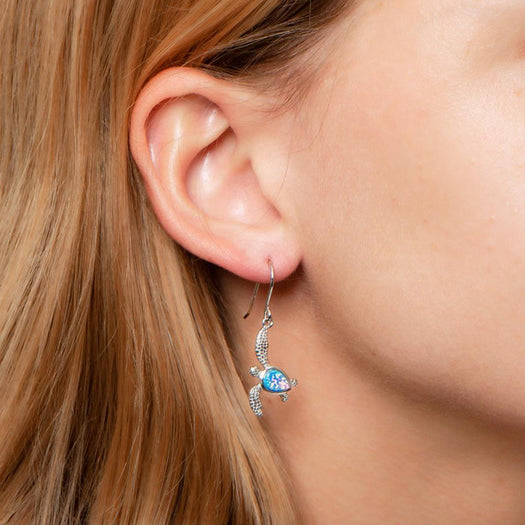 The picture shows a model wearing a 925 sterling silver opalite sea turtle earring.