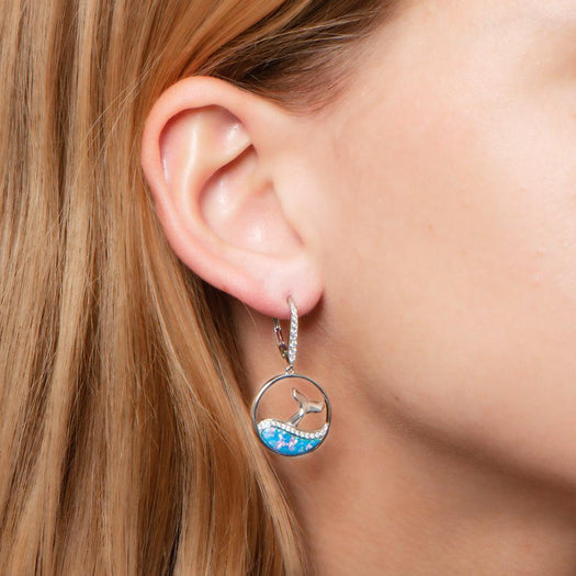 The picture shows a model wearing a 925 sterling silver opalite whale wave earring.