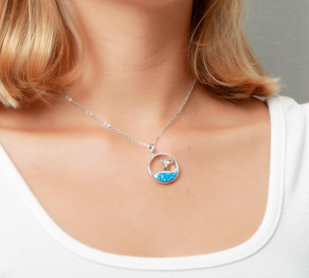 The picture shows a model wearing a 925 sterling silver opalite whale tail wave pendant with topaz.