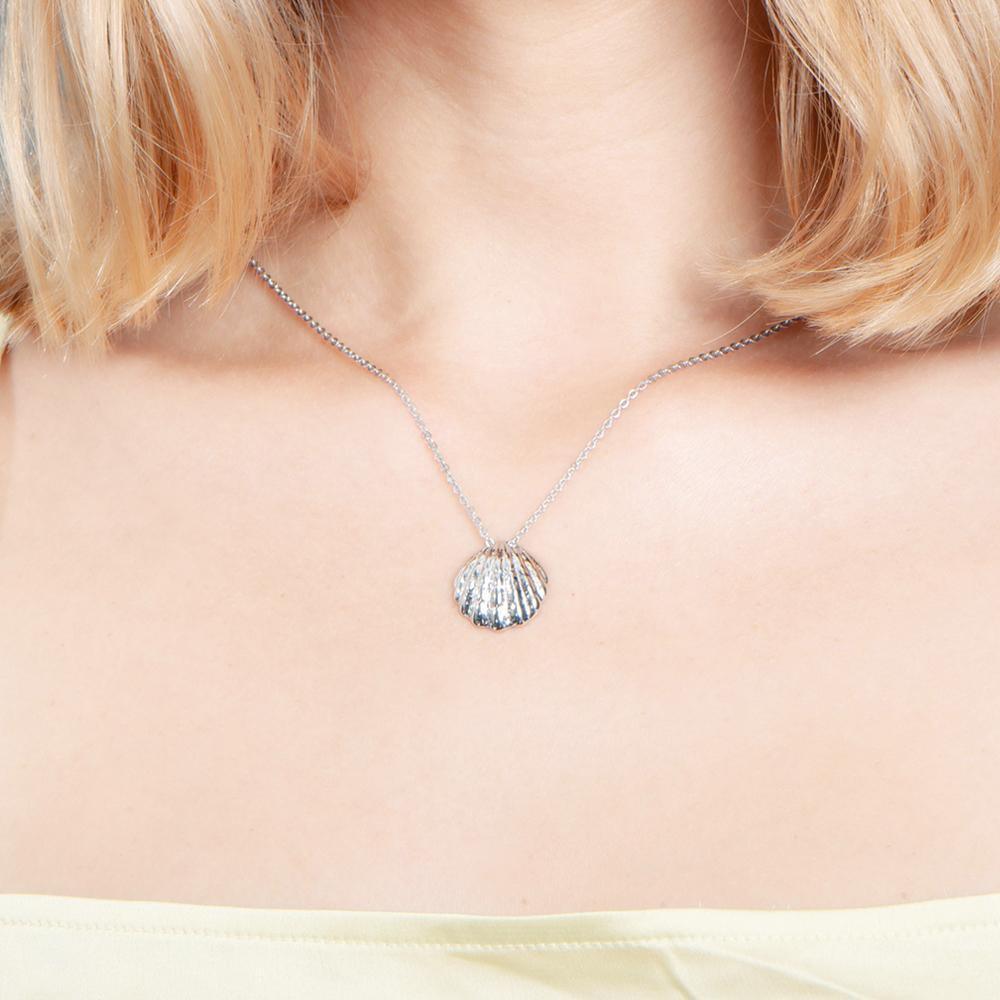 In this picture there is a model with blond hair and light yellow shirt wearing a sterling silver oyster shell pendant.