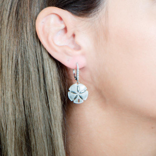 The picture shows a model wearing a 925 sand dollar earring with cubic zirconia.