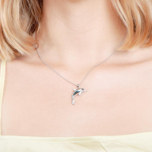 The picture shows a model wearing a 925 sterling silver dolphin pendant with cubic zirconia.