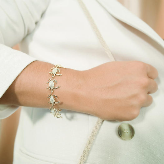 The picture shows a model wearing a 925 sterling silver yellow gold plated blue crab bracelet with topaz.