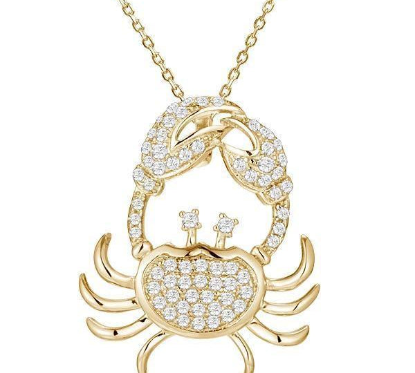 The picture shows a 925 sterling silver, yellow gold plated, pavé crab pendant with topaz.