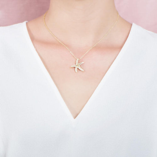 The picture shows a model wearing a 925 sterling silver, yellow gold plated, dancing starfish pendant with topaz.