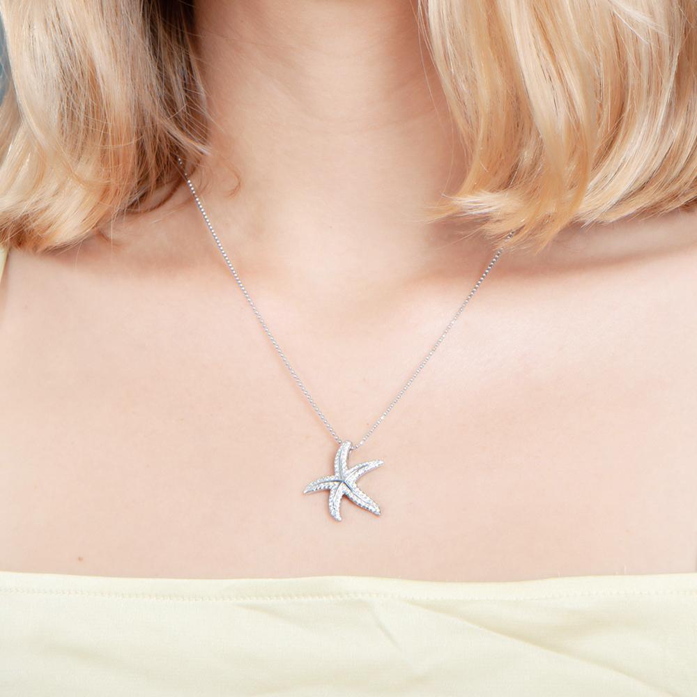 The picture shows a model wearing a 925 sterling silver, white gold plated, dancing starfish pendant with topaz.