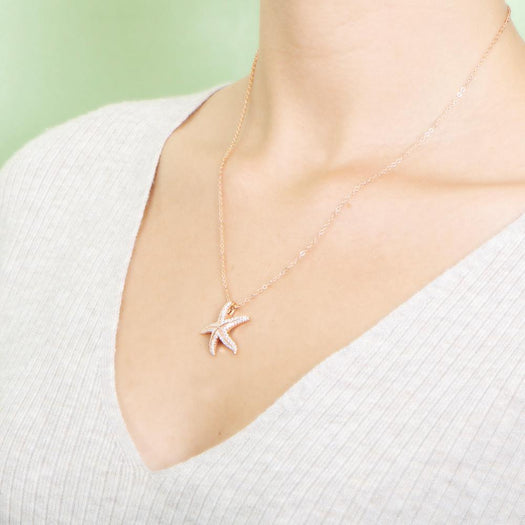 The picture shows a model wearing a 925 sterling silver, rose gold plated, dancing starfish pendant with topaz.