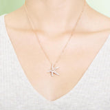 The picture shows a model wearing a 925 sterling silver, rose gold plated, dancing starfish pendant with topaz.